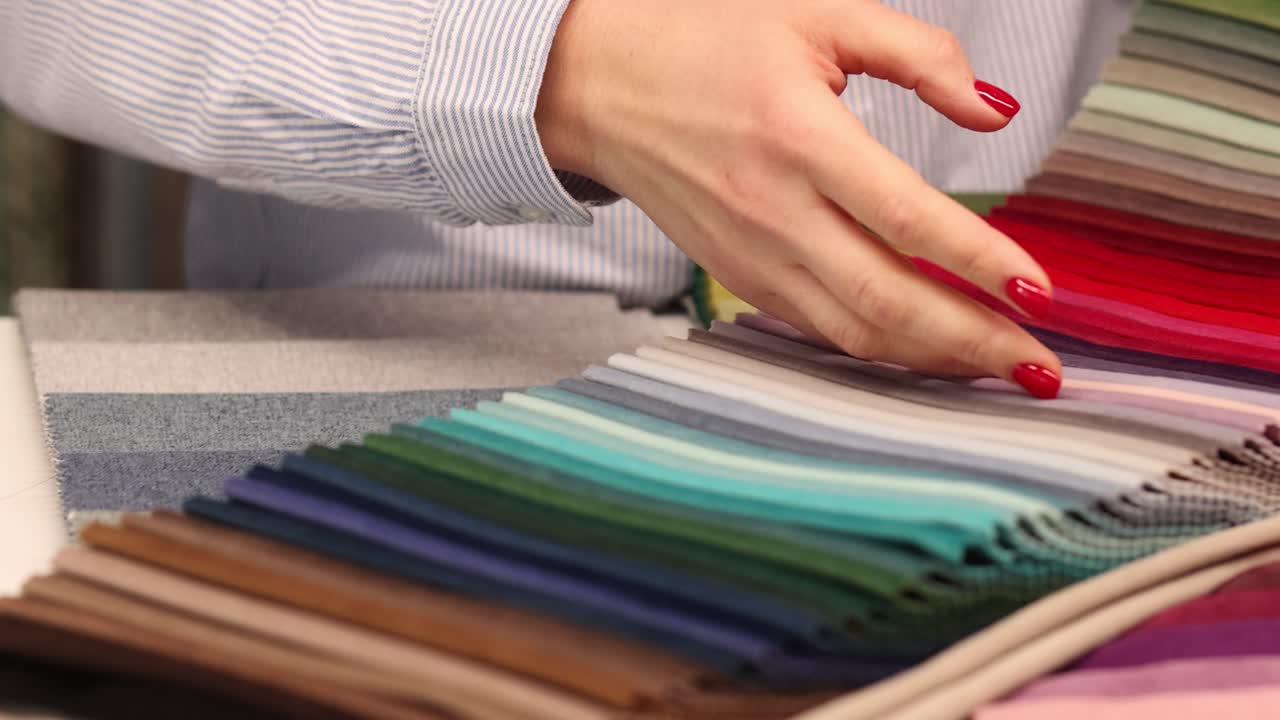 Person selecting colorful fabric swatches from a sample book