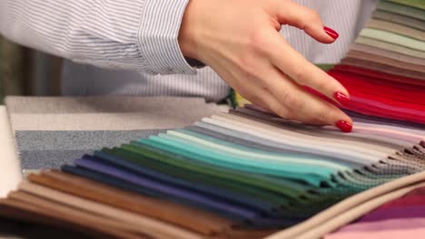 person selecting colorful fabric swatches from a sample book