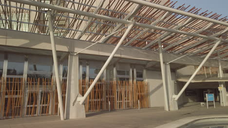 Pan-right-to-left-across-the-front-of-the-Scottish-Parliament-Building-at-Holyrood,-highlighting-architectural-detail,-on-a-sunny-day,-Edinburgh,-Scotland