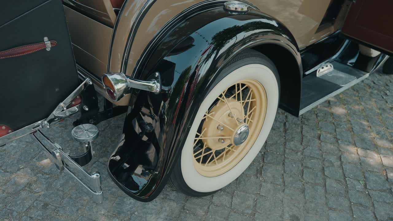 크림색 휠, 검은색 펜더, 세련된 여행용 트렁크와 광택 있는 크롬 장식이 돋보이는 클래식 자동차의 클로즈업 이미지
