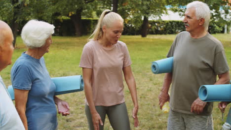 female trainer chatting with senior people before outdoor workout