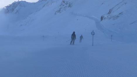 slalom skiers with backpacks riding down mountain slopes - handheld view
