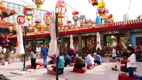 people gather under colorful lanterns at temple