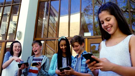 Grupo-De-Amigos-De-La-Escuela-Usando-Un-Teléfono-Móvil-Fuera-De-La-Escuela