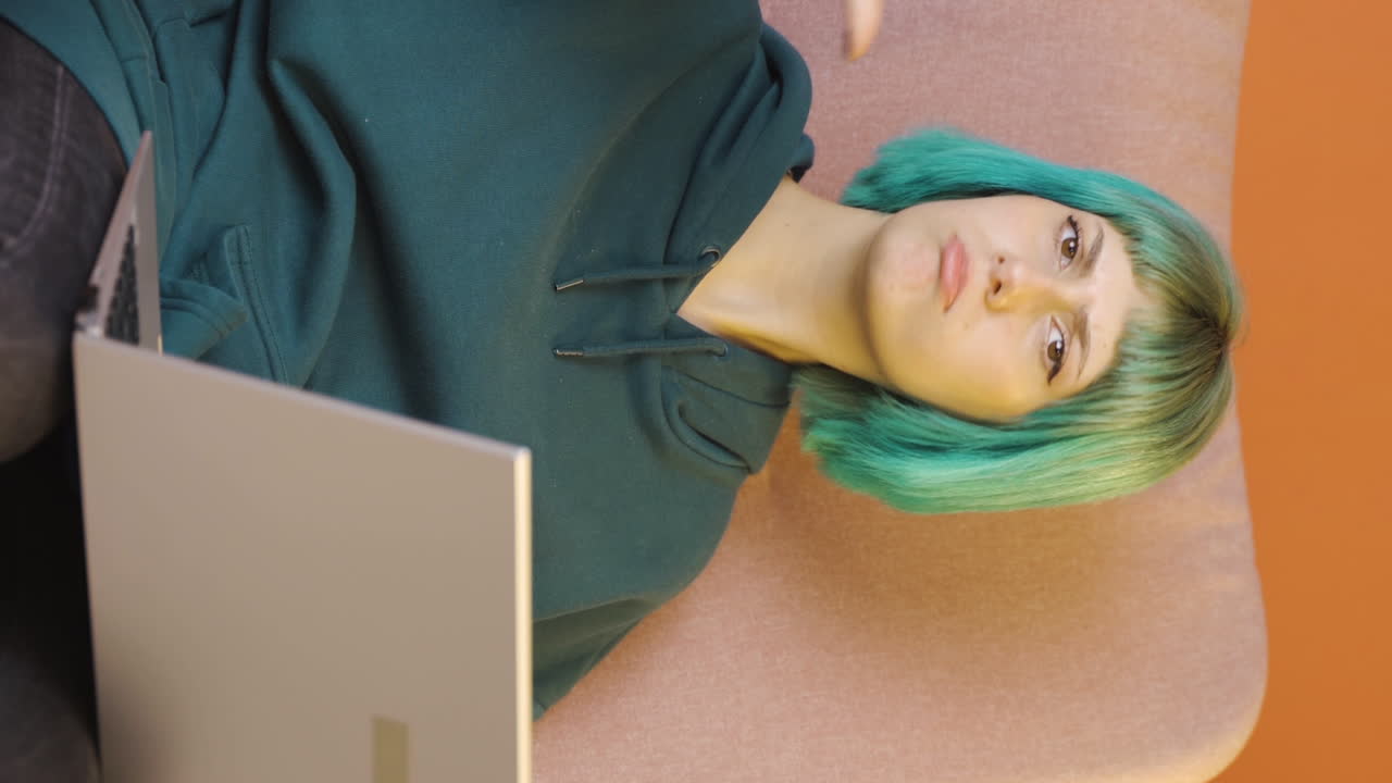 video vertical de expresión negativa de una mujer joven usando una computadora portátil.