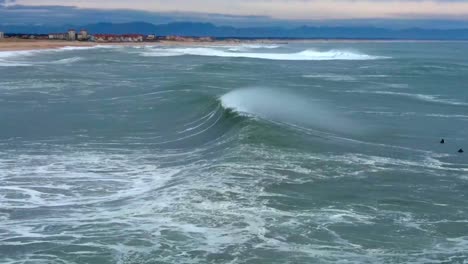 Vista-Horizontal-De-Drones-De-Una-Gran-Ola-Que-Choca-Contra-El-Rocío-De-Los-Vientos-Marinos-Temprano-En-La-Mañana-En-Hossegor,-Francia