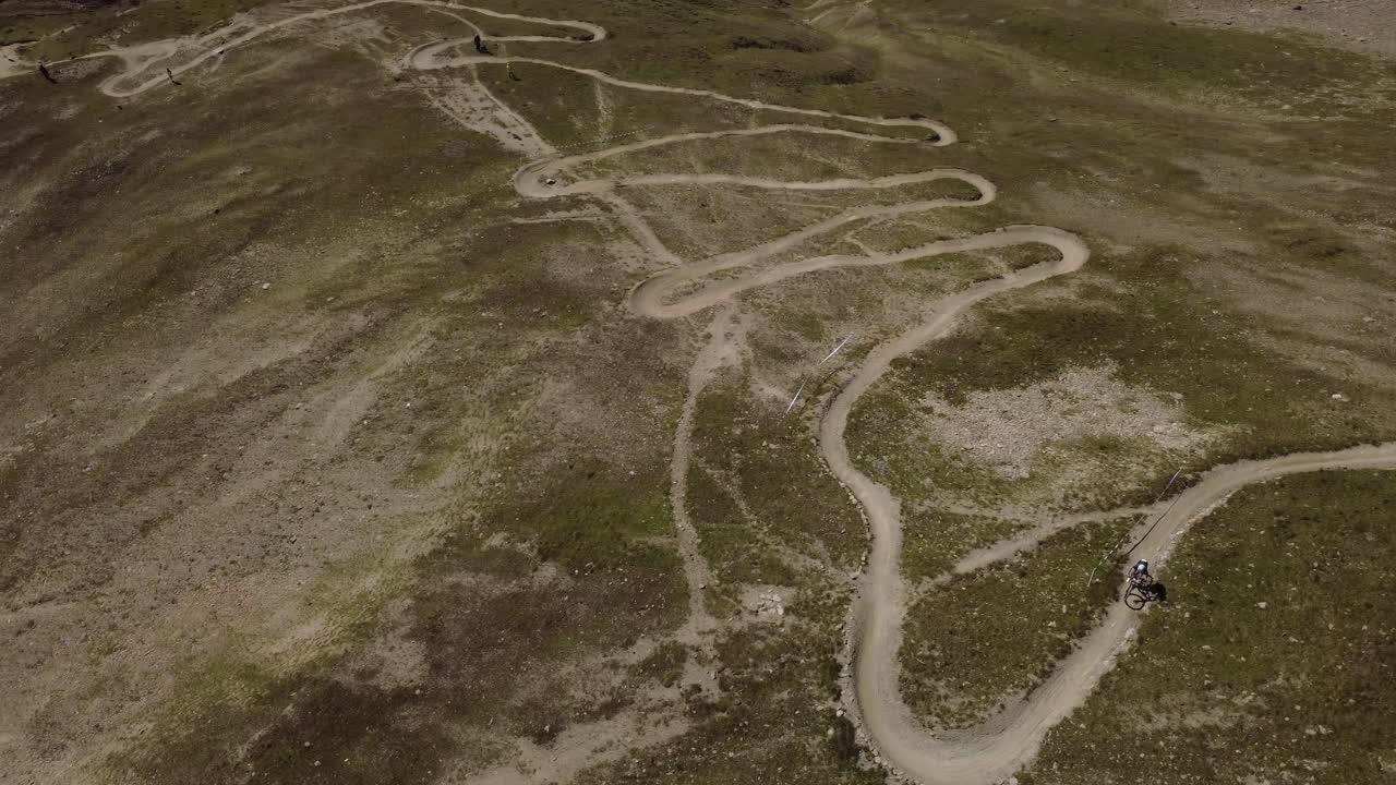 Drone footage of mountain bikers navigating technical corners on a rugged alpine trail in Ischgl, Austria. Great for MTB, sports, and tourism themes