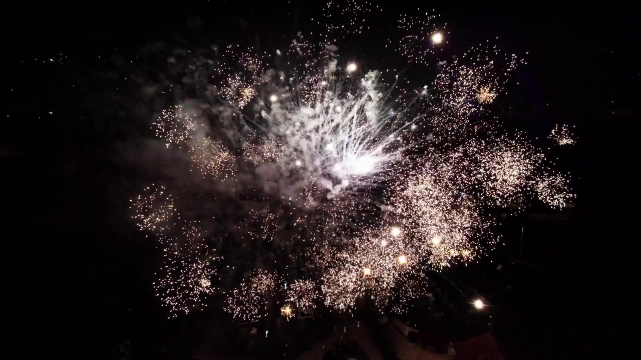 Ripresa aerea con drone di fuochi d'artificio luminosi che esplodono nel cielo notturno scuro