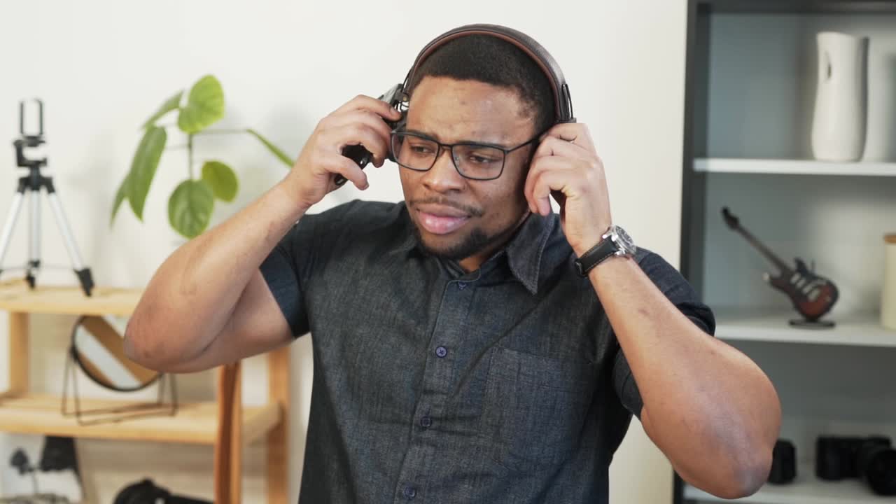 un hombre carismático de piel oscura se pone los auriculares y comienza a bailar y cantar