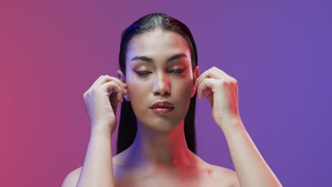 mujer biracial con cabello negro y maquillaje tocando su cara, copia espacio, cámara lenta