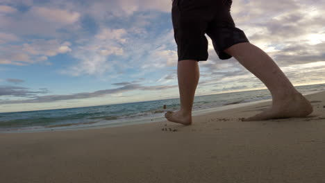 piernas y pies descalzos caminando hacia el océano en la playa con olas