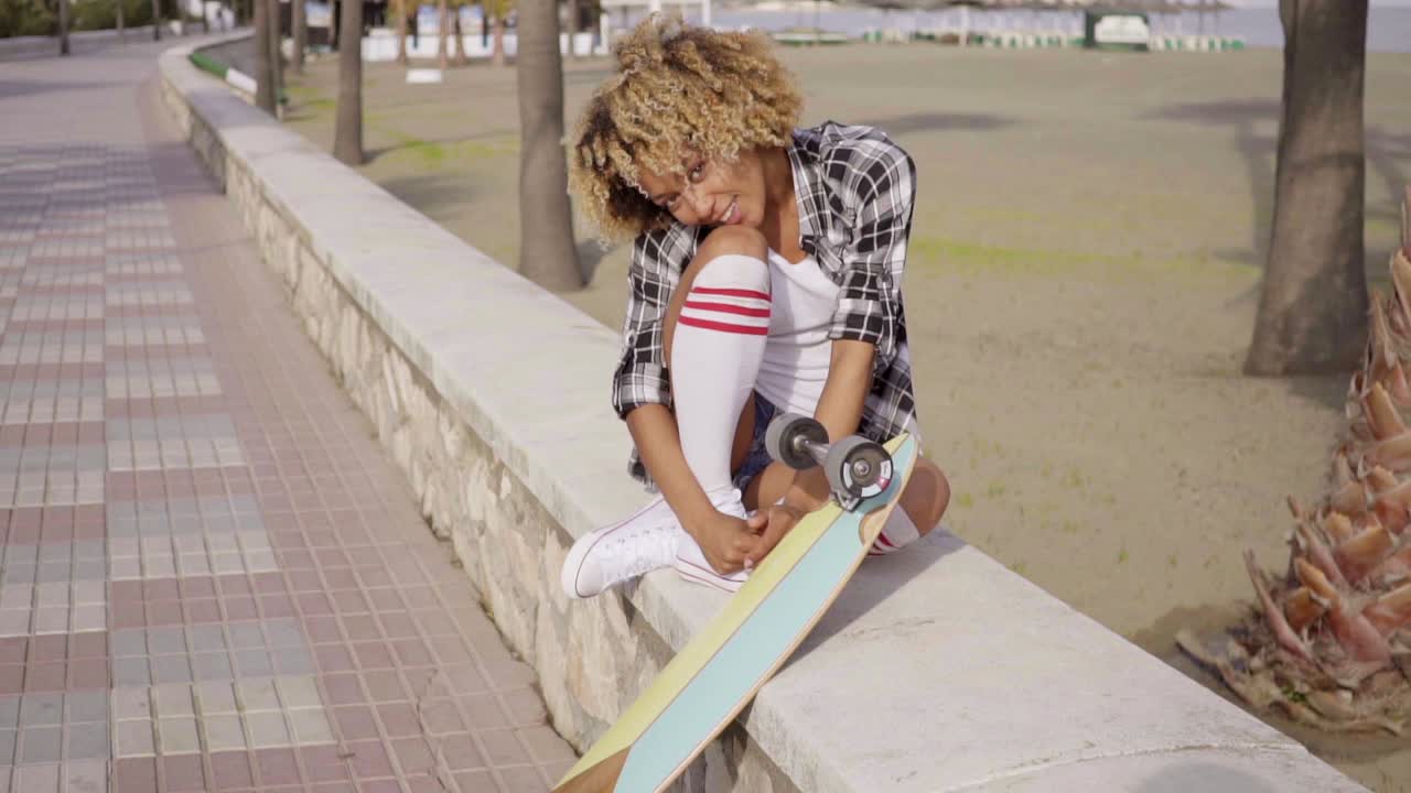 Cute teenager sitting on ledge with skateboard