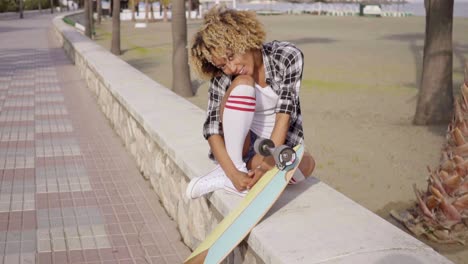 Cute-teenager-sitting-on-ledge-with-skateboard