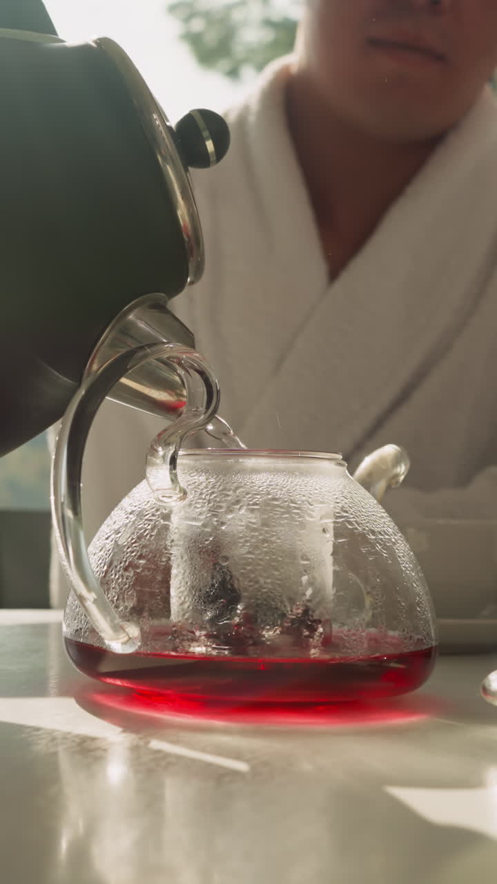 한 남자가 비에서 물을 차에 부어, 젊은이의 도움으로 점차 물로 채우면서 만든 과일 차. 뜨거운 음료가 있는 식탁.