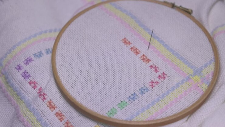 Establishing shot of a baby blanket cross-stitch pattern sitting on a woman lap