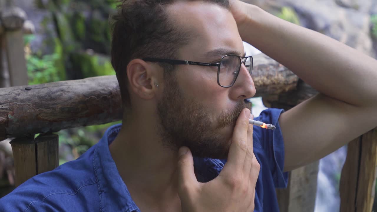 un joven fumando en la ciudad.
