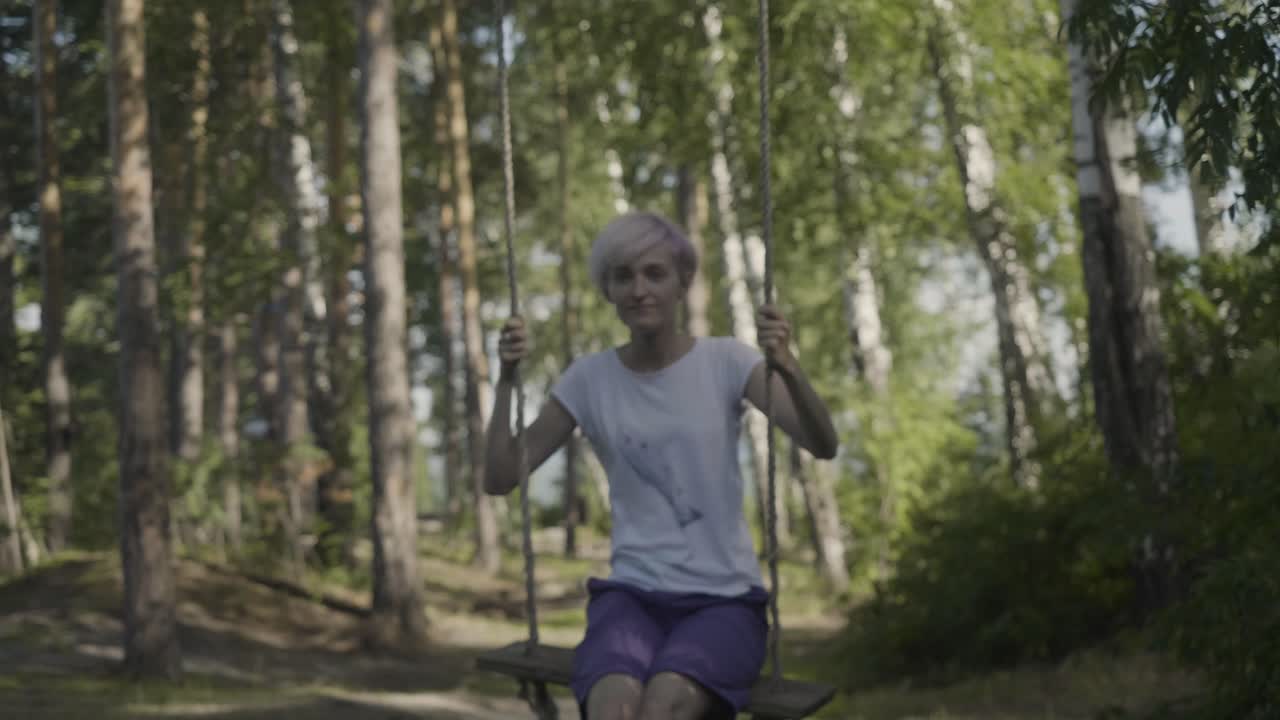 una mujer balanceándose en un bosque.