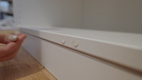 close-up of hands sticking protective rubber bumper on white closet