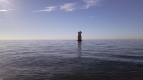 vista al mar con una antigua torre de cable aéreo en el horizonte