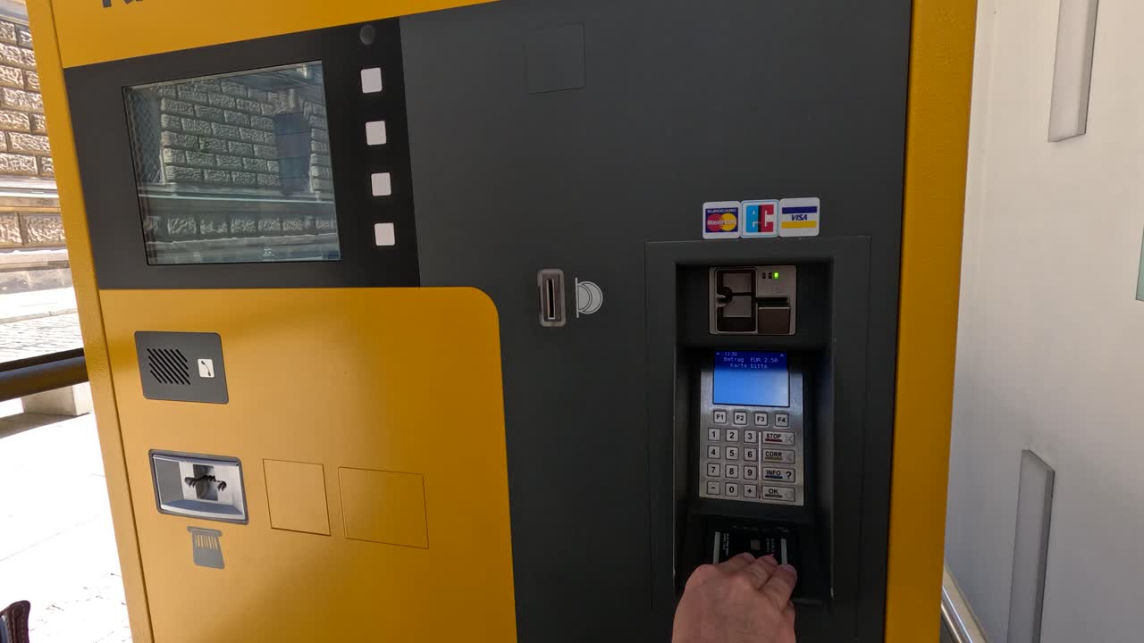 Person entering PIN at yellow ticket machine in Dresden transit station during daylight