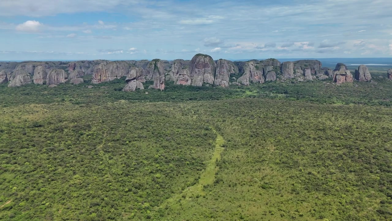 Impressionante vista aérea dos famosos monólitos de rocha gigantes Pedras Negras de Pungo Andongo, com um caminhante em um mirante elevado contra um céu azul na Província de Malanje, Angola.