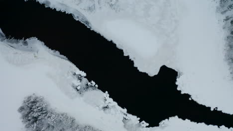 Aerial-view-looking-down-above-cold-winter-woodland-lake-in-Norbotten-Swedish-landscape