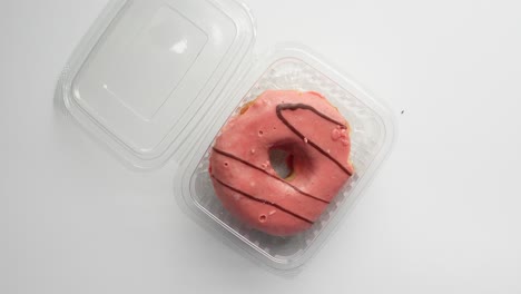 pink glazed donut in a plastic container