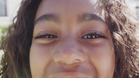 portrait of happy african american girl looking at camera and smiling in garden, slow motion