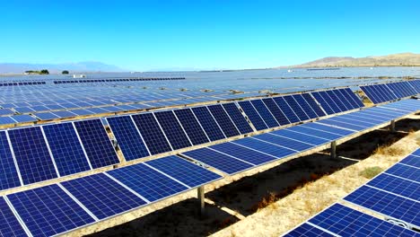 lateral aerial drone sweep and pan over huge solar photovoltaic panel power generating farm in desert with reflecting sun, 4k
