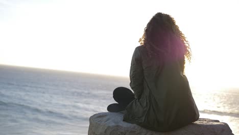 slow motion of a girl looking at the beach and posing with hair flying with the wind