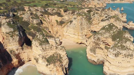 playa de gruta aislada rodeada de acantilados erosionados de la naturaleza de ponta da piedade, lagos, algarve - tiro panorámico aéreo