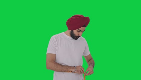 sad sikh indian man measuring waist using inch tape green screen