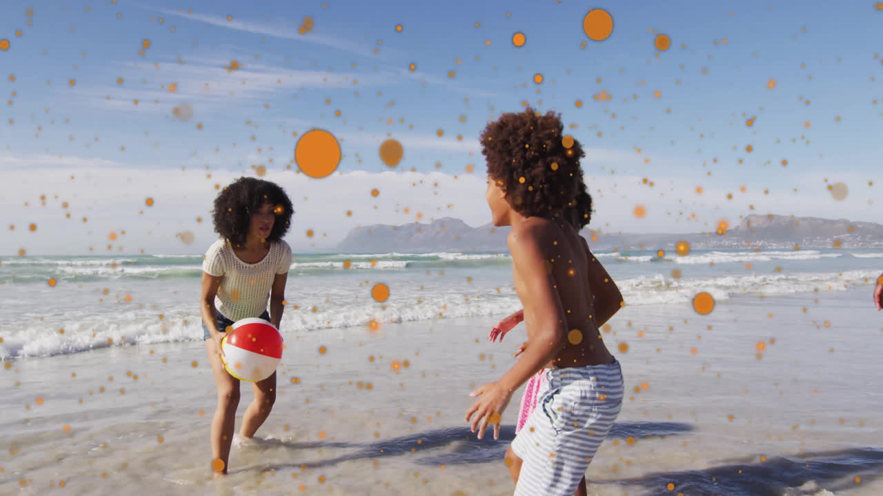 Playing with beach ball, children enjoying beach day over orange particles animation