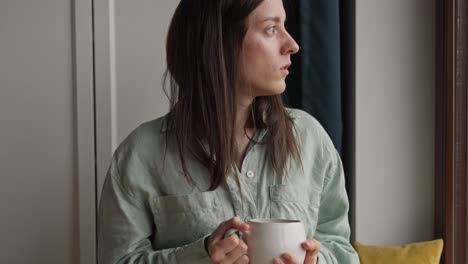 woman drinking coffee/tea by the window