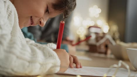 handheld video of little boy focused on writing letter to santa claus