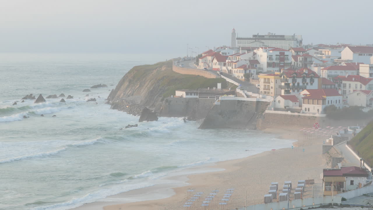 포르투갈 레이리아의 안개 낀 아침에 마을이 보이는 상 페드로 데 모엘 해변의 거친 파도