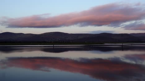 a perfect view of the water and the mountains, the clouds reflecting on the water and the flock of birds flying