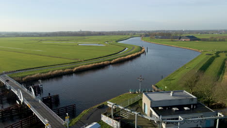 jib up of small bridge with pumping station over river in a typical dutch landscape with green meadows