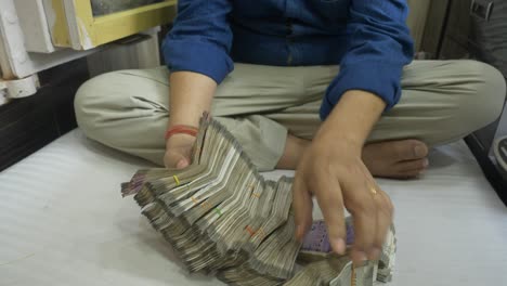 a businessman counting stack of indian banknotes, cash in hand, lots of cash, wide angle shot