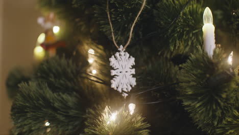la cámara se enfoca en el copo de nieve colgando del árbol de navidad con luces