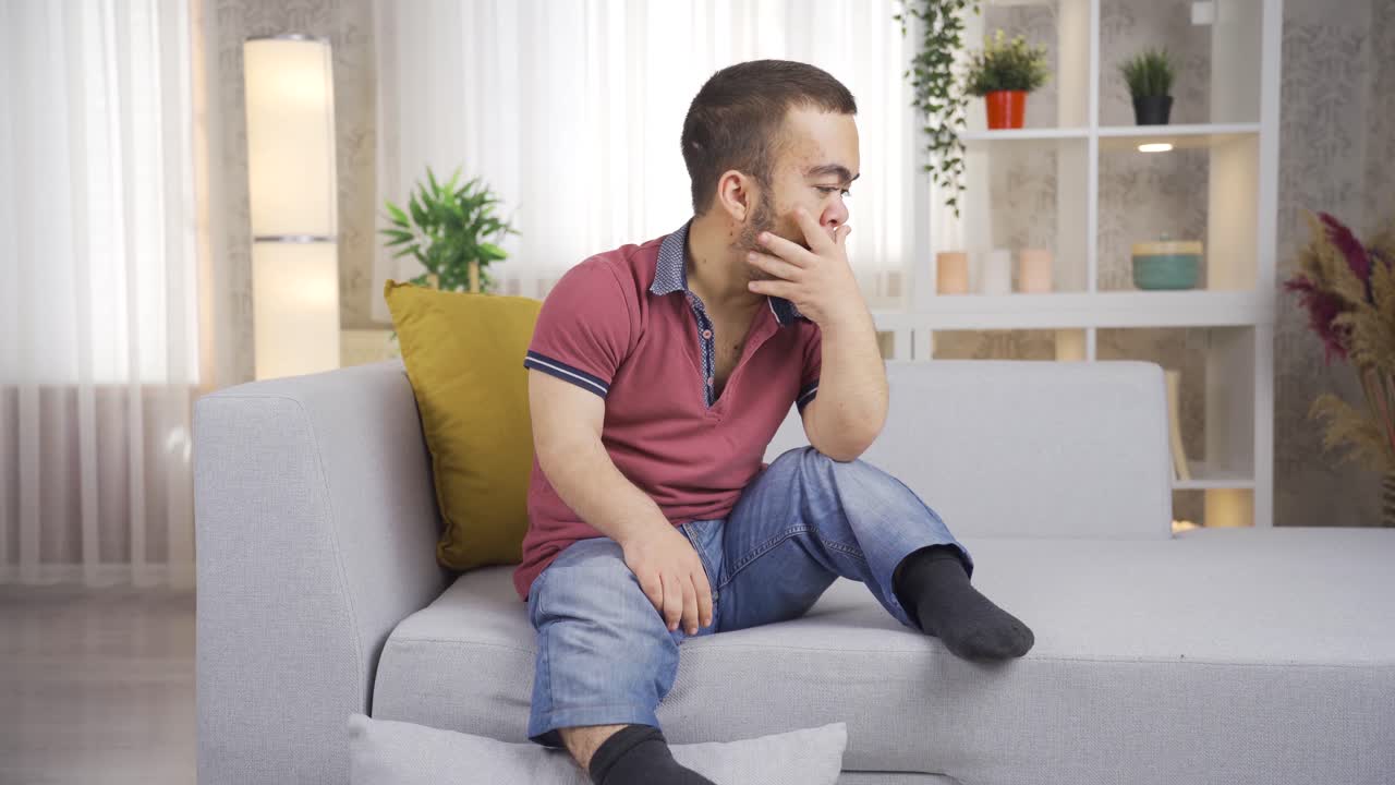 난쟁이증을 가진 젊은 남자는 집에서 사려 깊고 슬프다.