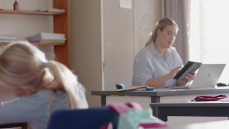 in school, female teacher working on laptop at desk in classroom, concentrating