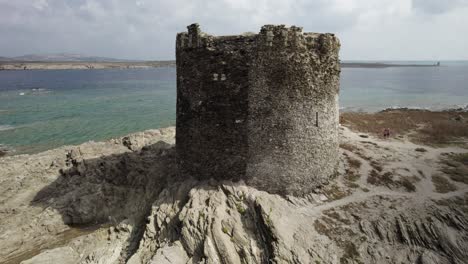 Luftumlauf-über-Dem-Mittelalterlichen-Wachturm-Von-Pelosa-Auf-Der-Felsigen-Insel,-Umgeben-Vom-Smaragdgrünen-Meer