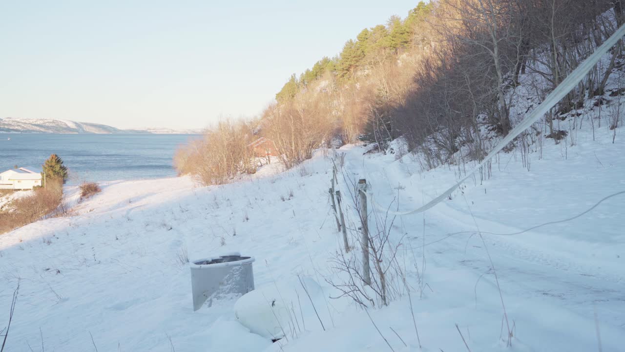노르웨이의 바다 전망과 함께 겨울에 눈 덮인 길을 걷는 배낭을 메고 개와 야영자