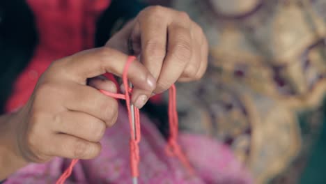 Woman-starting-a-first-row-of-knitting-with-red-thread-and-needle-crafts