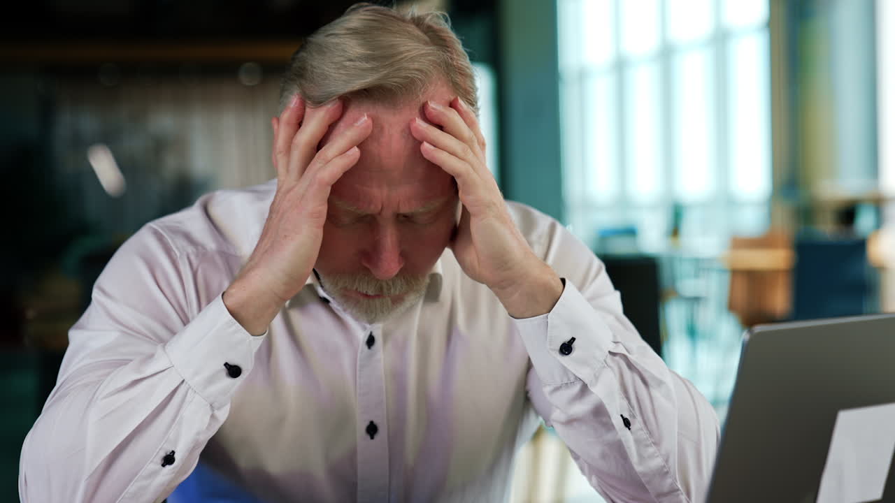 Tired bearded man in shirt rubs his face feeling tired. Businessman burnt out at hard work. Close up portrait.