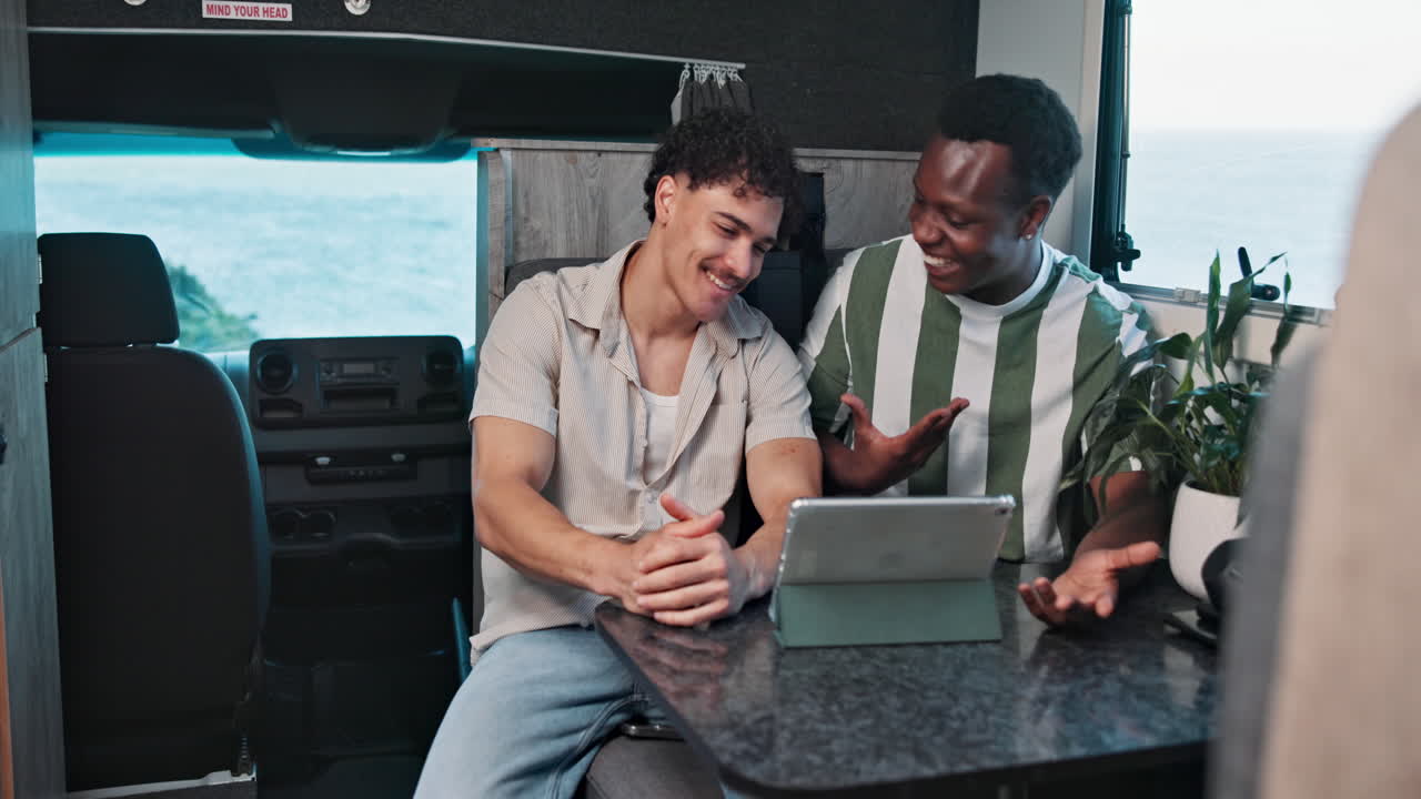 Two Young Men Talking and Laughing While Using a Tablet in a Camper Van