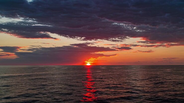 Tramonto rosso intenso che si riflette sulla superficie dell'oceano