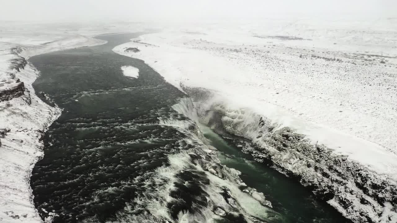 Aerial footage capturing the Hvítá River cutting through the rugged canyon near Gullfoss waterfall during wintertime.