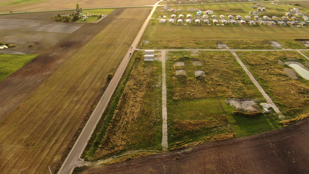 도로를 달리는 차량이 있는 푸른 초원의 개인 주택 지구, 공중의 황금빛 일몰 전망